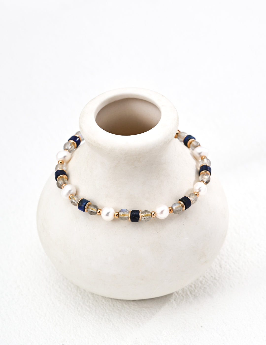 This S925 silver bracelet features a stunning combination of grey moonstone, natural pearls, and lapis lazuli. The soft glow of the moonstone paired with the rich blue of the lapis lazuli and the elegance of pearls creates a timeless design, perfect for both everyday wear and special occasions.