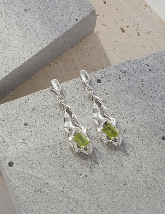 These minimalist drop earrings feature natural peridot gemstones in a sleek, modern design. The soft green sparkle of the peridot adds a subtle pop of color, making them ideal for everyday elegance or as a unique August birthstone gift. Perfect for those who love simple yet refined handcrafted jewelry.