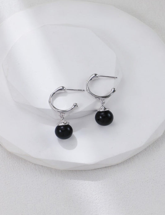These S925 silver earrings feature smooth black onyx stones, offering a sleek and minimalist design. Their deep black hue and refined setting make them a versatile accessory for daily wear or elegant occasions. A perfect choice for those who value classic style and natural gemstones.